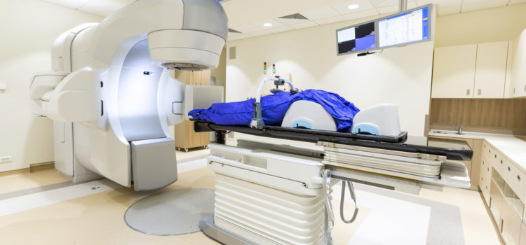 Strålning för behandling av cancer sker på en brits med maskin som ger strålning.